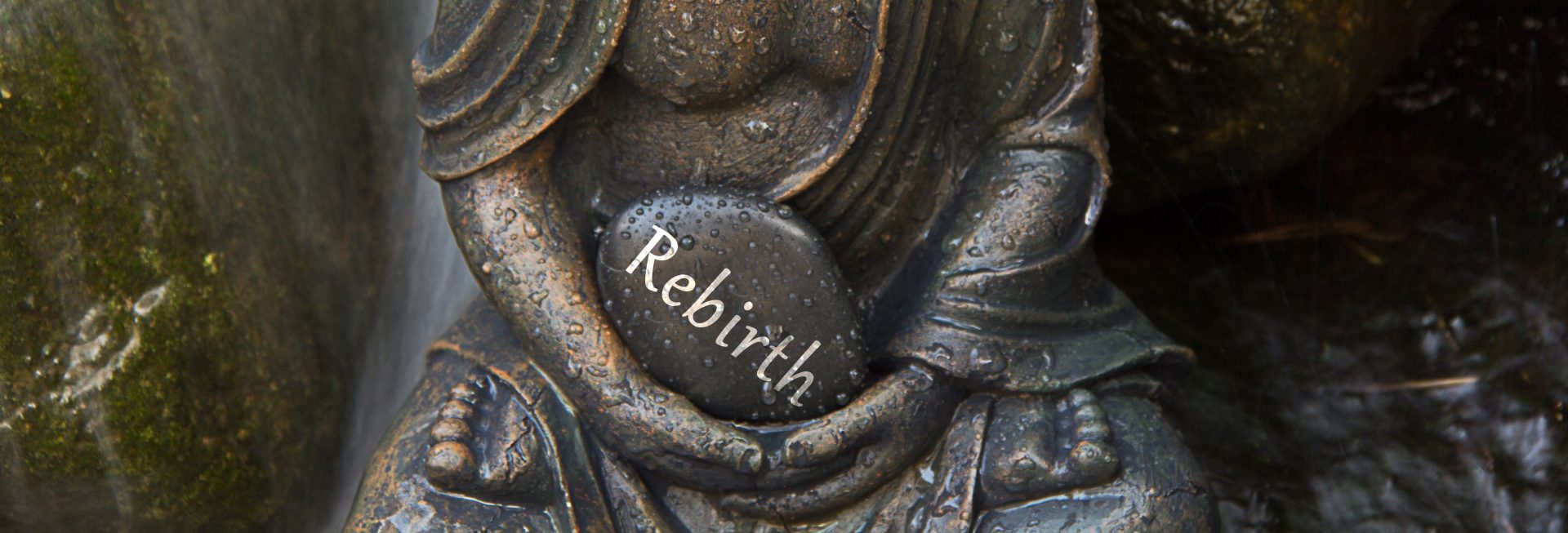 Les mains d'une statue de Bouddha tiennent un galet sur lequel est écrit REBIRTH